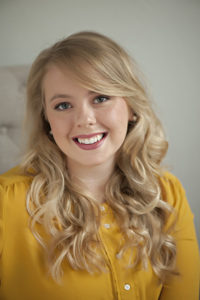 Business headshot of a young blond woman in a yellow shirt. Headshots can be used for business or personal purposes.